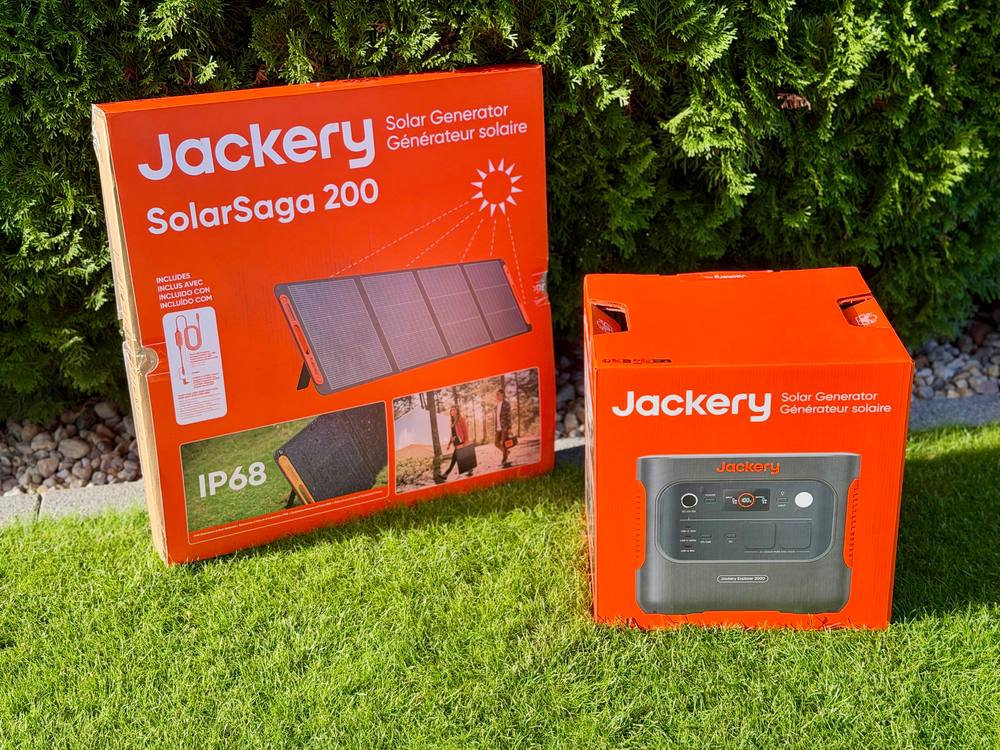 Zwei Kartons auf dem Rasen: links der große Karton des SolarSaga 200 mit IP68-Hinweis, rechts der Karton der Powerstation