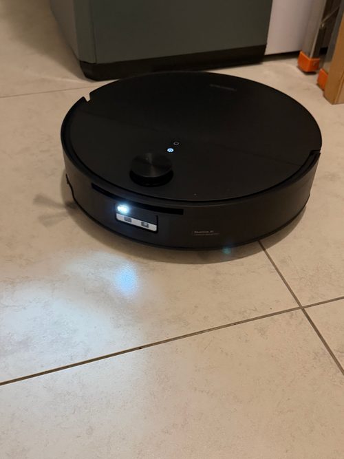 Roborock Saros 20 Flow fährt über helle Fliesen, der runde Laserturm ist ausgefahren, vorn leuchtet das Licht am Kameramodul