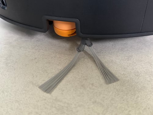 Seitenbürste des Roborock Saros 20 Flow mit zwei grauen Borstenbündeln, darüber die orangefarbene Halterung in einer Aussparung des Gehäuses