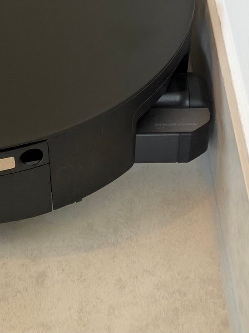 Roborock Saros 20 Flow von oben an einer Fußleiste, seitlich ragt die ausgefahrene Walze in ihrem schwarzen Gehäuse bis dicht an die Leiste