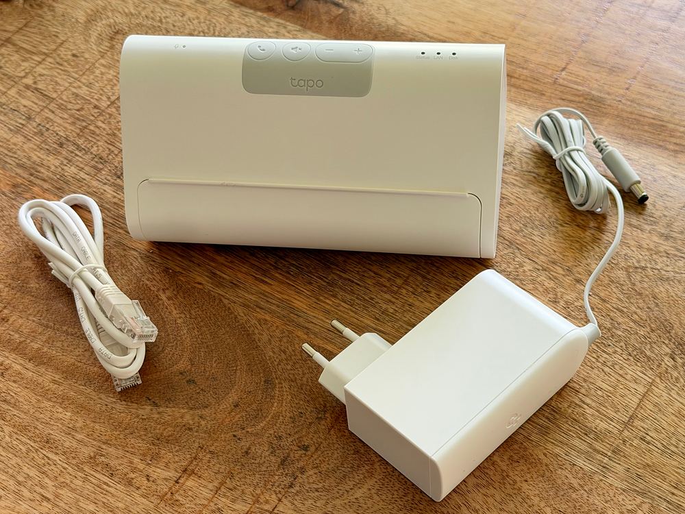 Tapo H500 CentralHub mit Netzteil und LAN-Kabel auf einem Holztisch